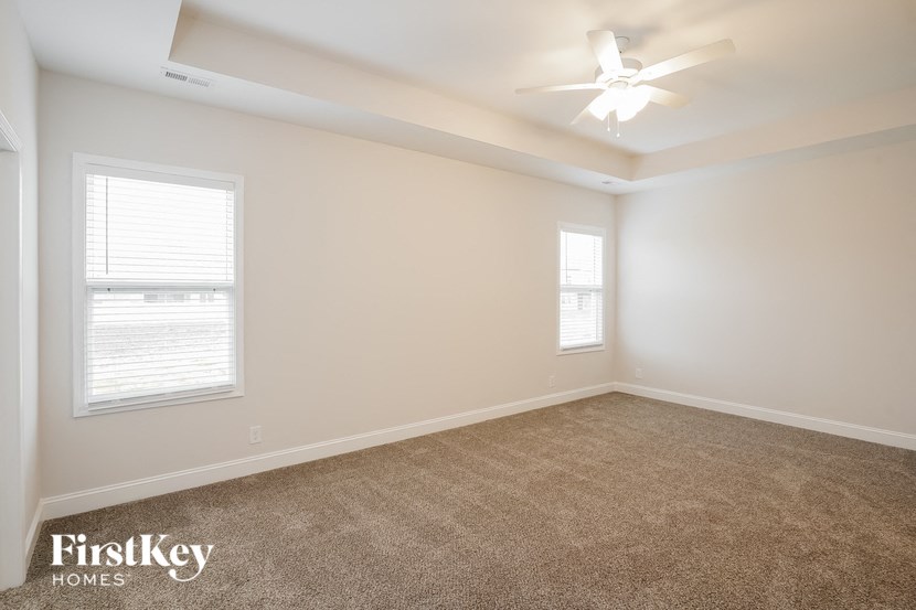 an empty room with a ceiling fan and two windows