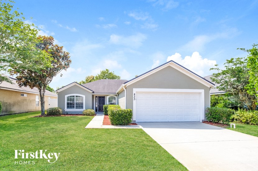 a beige house with a garage door and a lawn