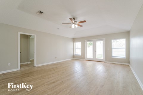 an empty living room with wood floors and a ceiling fan