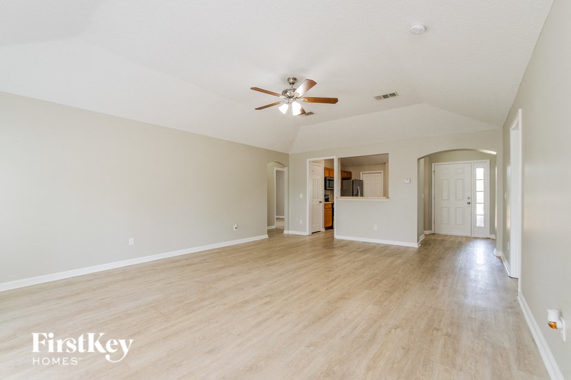 the living room and dining room of an empty house with a ceiling fan