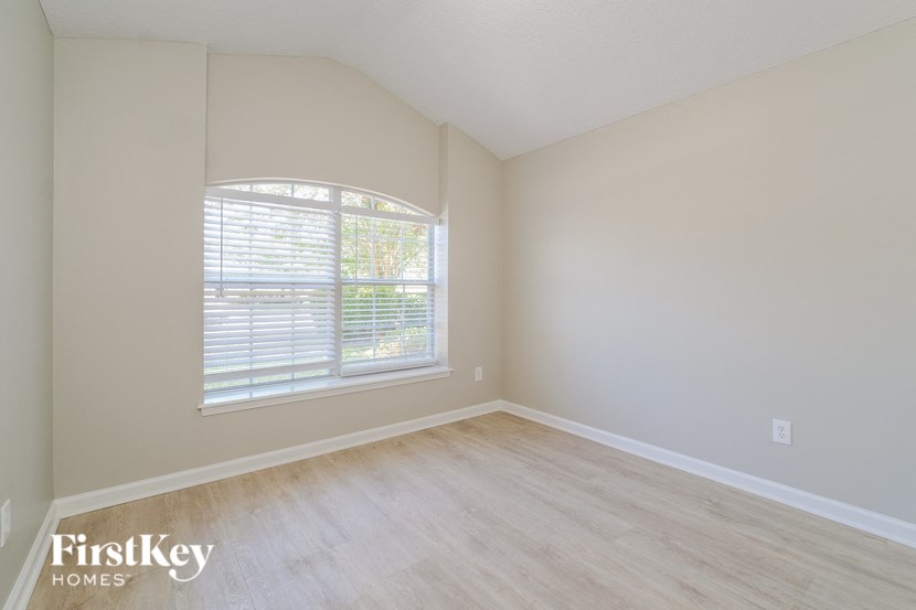 a bedroom with wood floors and a large window