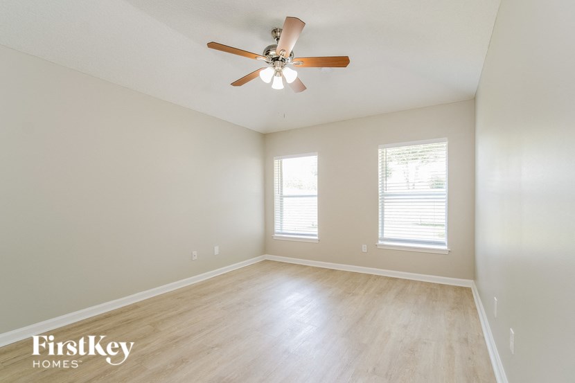 an empty living room with a ceiling fan and wood floors