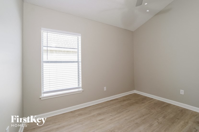 a bedroom with wood floors and a window and white walls