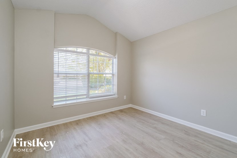 a bedroom with wood floors and a large window