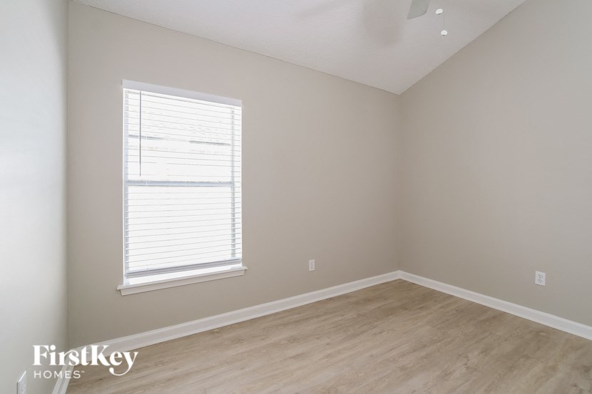 a bedroom with a wood floor and a window