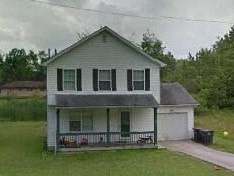 A white house with a green door and a grey roof.