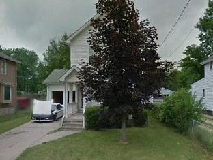 A white house with a tree in front of it.