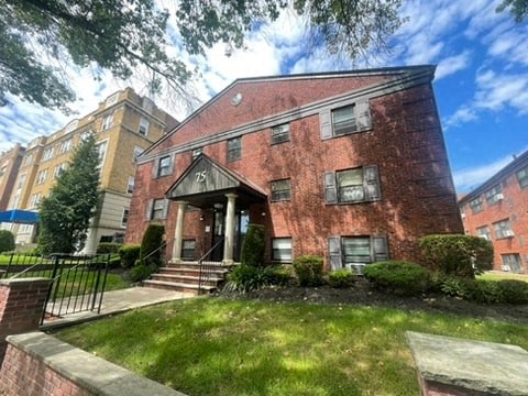 the front of a red brick house with a grassy yard