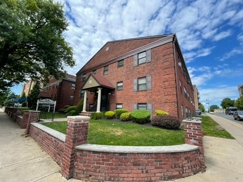 A red brick building with a green lawn in front.