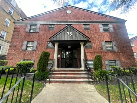 A red brick building with a black door and steps leading up to it.