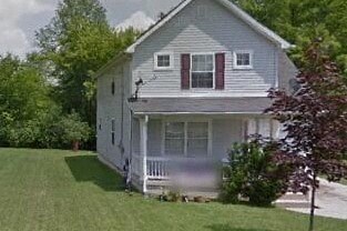 A house with a grey roof and red shutters.