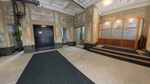A black door is on the left side of a hallway with a green carpet.