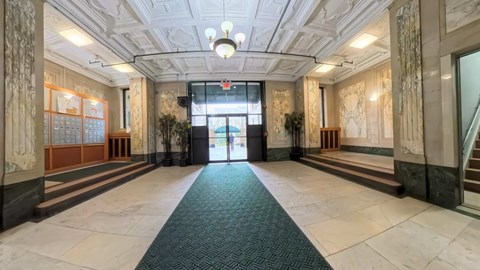 A hallway with a green carpet and a staircase on the right.