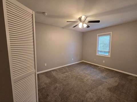 a bedroom with a ceiling fan and a window