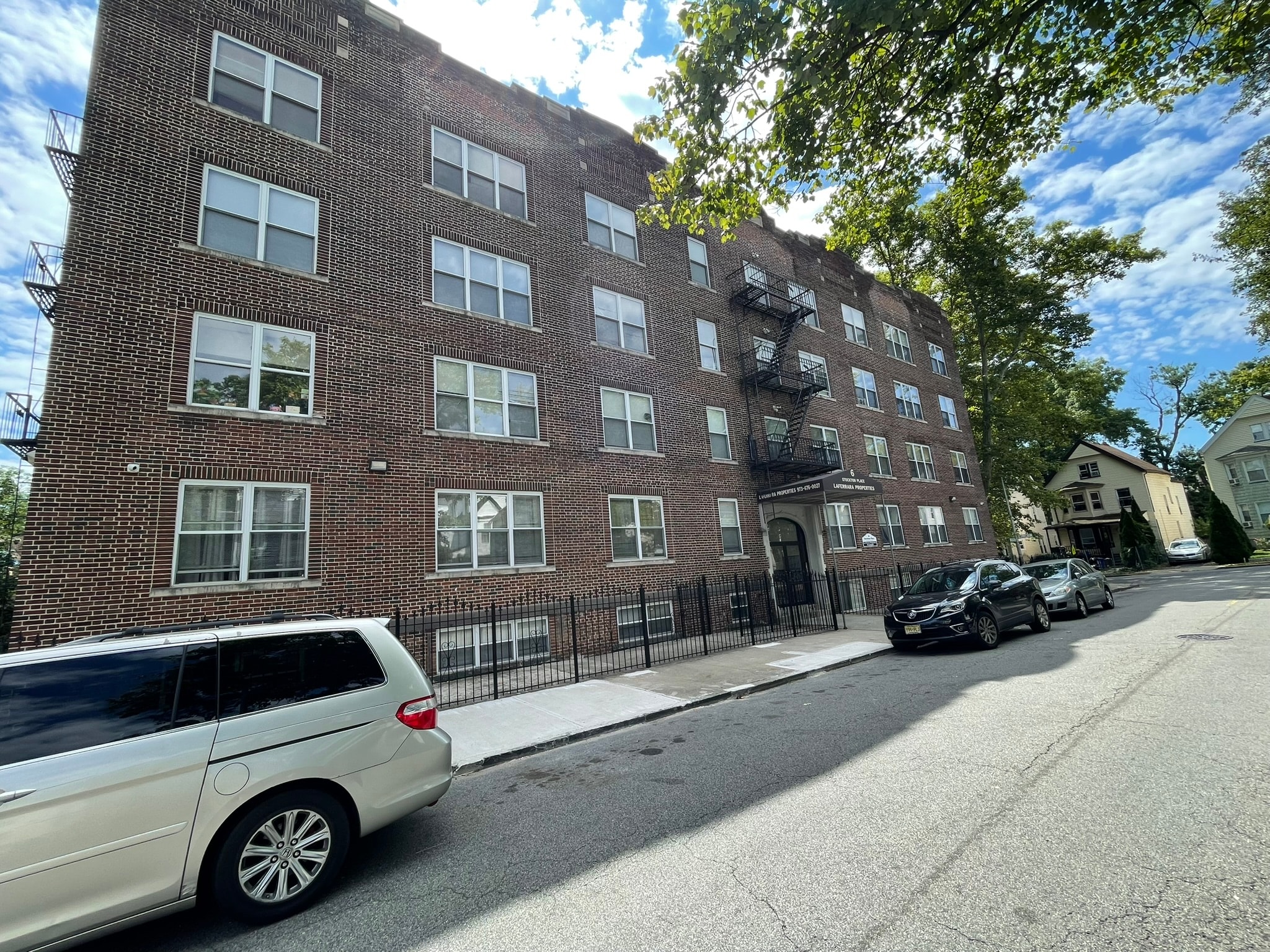 A white car is parked on the side of a street in front of a brick building.