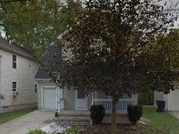 A house with a white garage door is surrounded by a small garden.