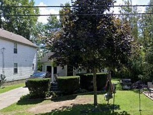 A white house with a tree in front of it.