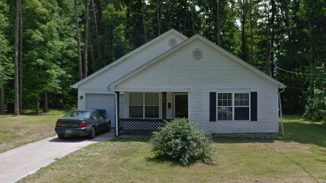 A small white house with a car parked in front.
