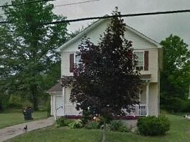 A white house with a tree in front of it.