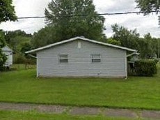 A small house with a grey roof and a white wall.