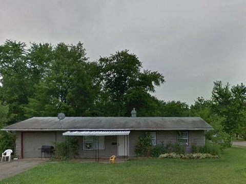 A house with a grey roof and a white chair in front of it.