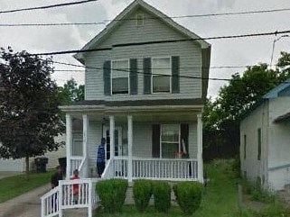 A white house with a porch and a person sitting on it.