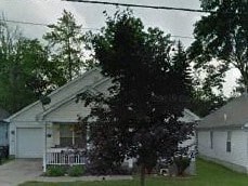 A house with a white garage door and a tree in front.