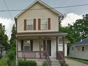 A small house with a porch and a brown door.