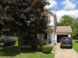 A white house with a black car parked in front.