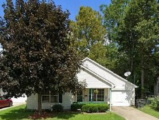 A white house with a green lawn in front.