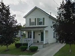 A white house with a green door and a porch.