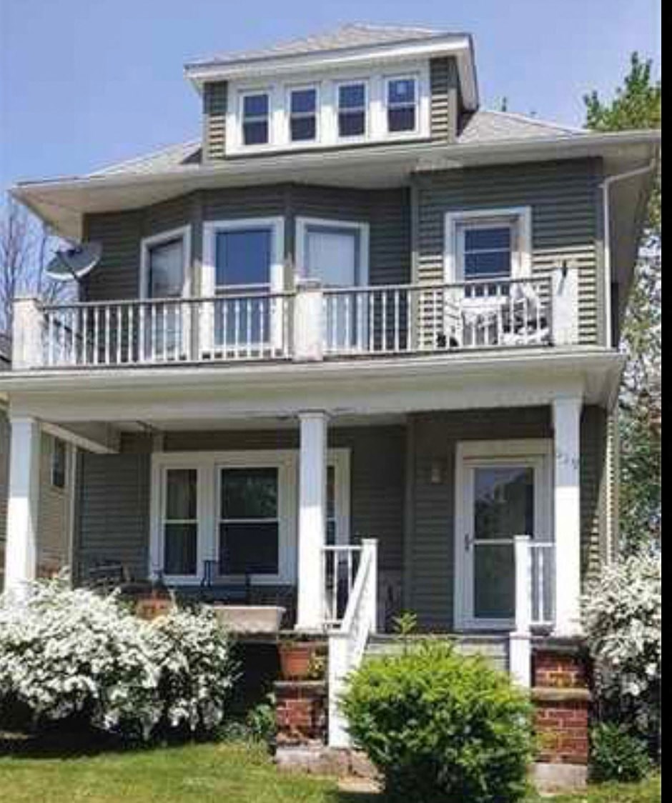 A two-story house with a balcony and white railings.