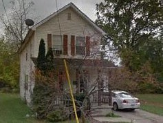 A white car is parked in front of a house.
