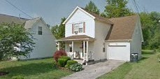 A white house with a brown roof and a small porch.
