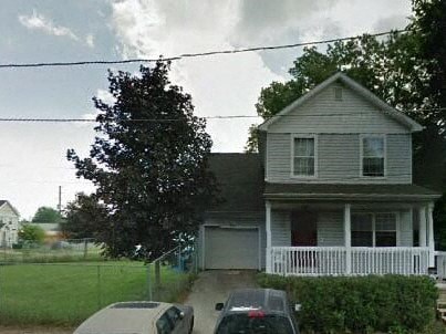 A house with a white fence and a tree in front of it.