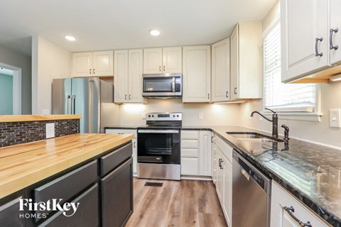 A kitchen with a wooden counter top and stainless steel appliances.