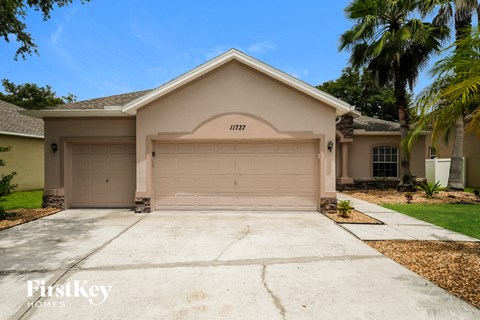 a beige house with a garage door and a driveway