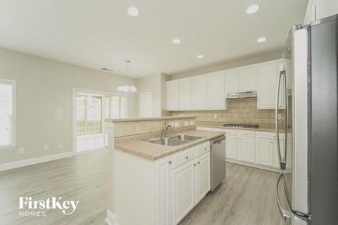 a white kitchen with white cabinets and a stainless steel refrigerator