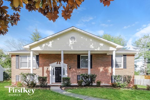 a brick house with a white front porch and a lawn
