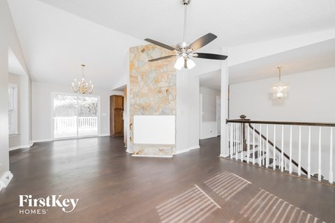 an empty living room with a ceiling fan and a staircase
