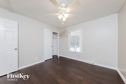 a bedroom with white walls and a ceiling fan and wood floors
