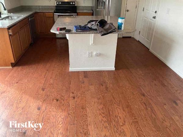 A kitchen with wooden floors and a white island in the middle.