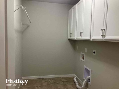 a kitchen with white cabinets and a wall with a closet and a staircase