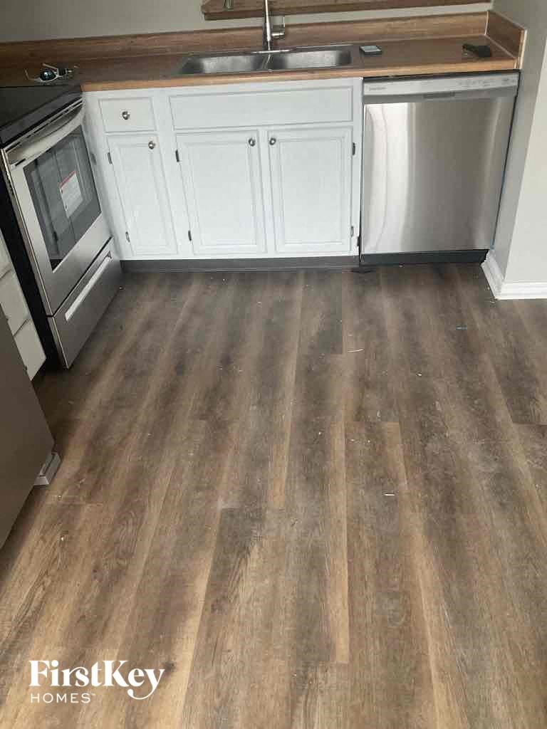A kitchen with wooden floors and white cabinets.