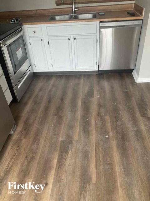 A kitchen with wooden floors and white cabinets.
