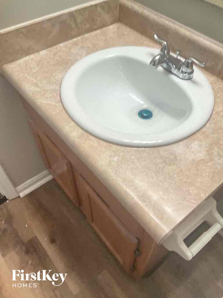 A white sink with a silver faucet in a marble countertop.