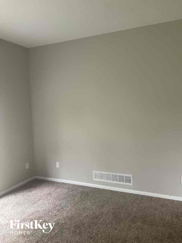 A room with a carpeted floor and a wall-mounted air vent.