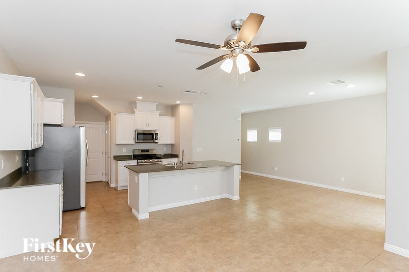 A spacious kitchen and living room with a ceiling fan.
