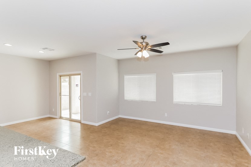 A spacious room with a ceiling fan and a rug on the floor.