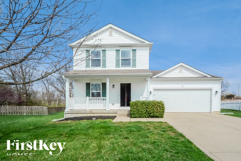 A white two-story house with a garage and a tree in the front yard.